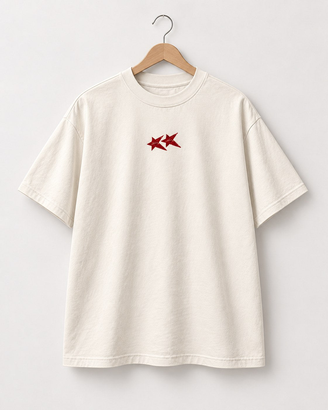 Face du t-shirt crème Build Society sur cintre, deux étoiles rouges sur la poitrine